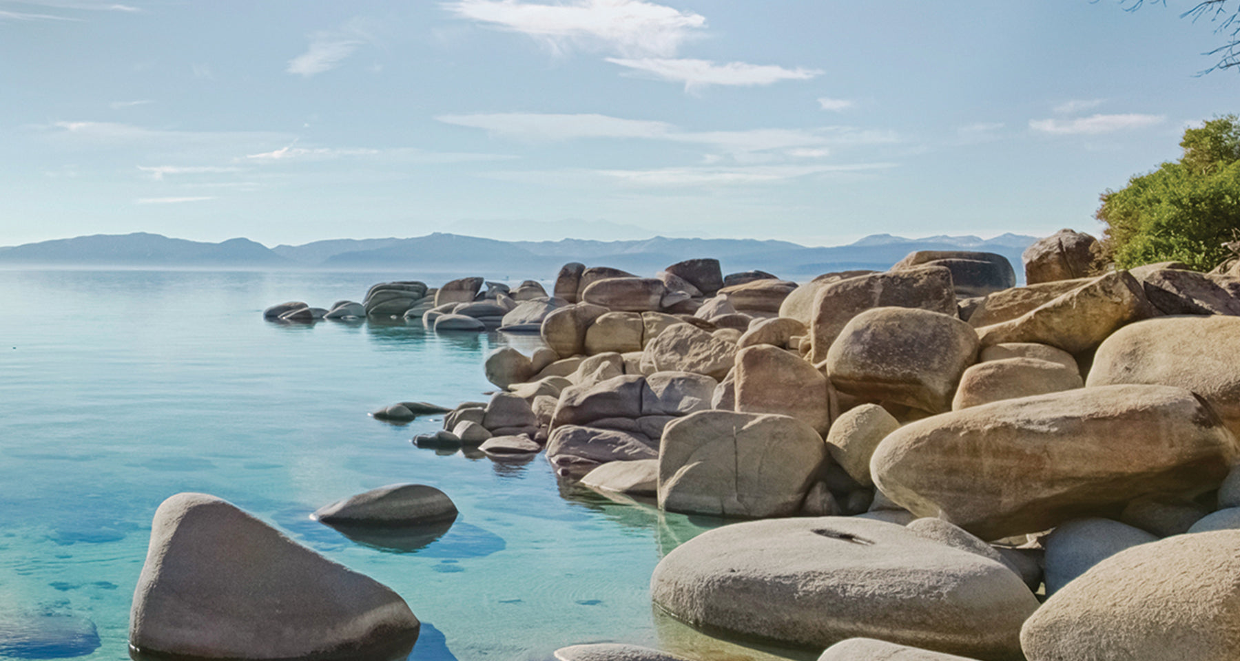 Rocks by a body of water with mountains in the background