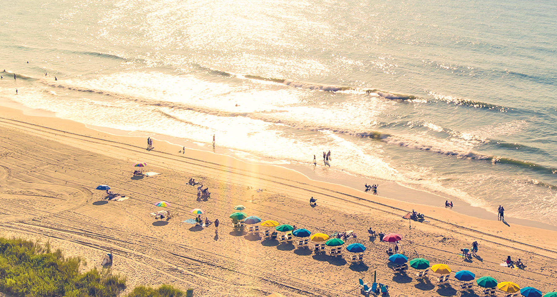 Beach scene with colorful umbrellas and people under a clear sky.